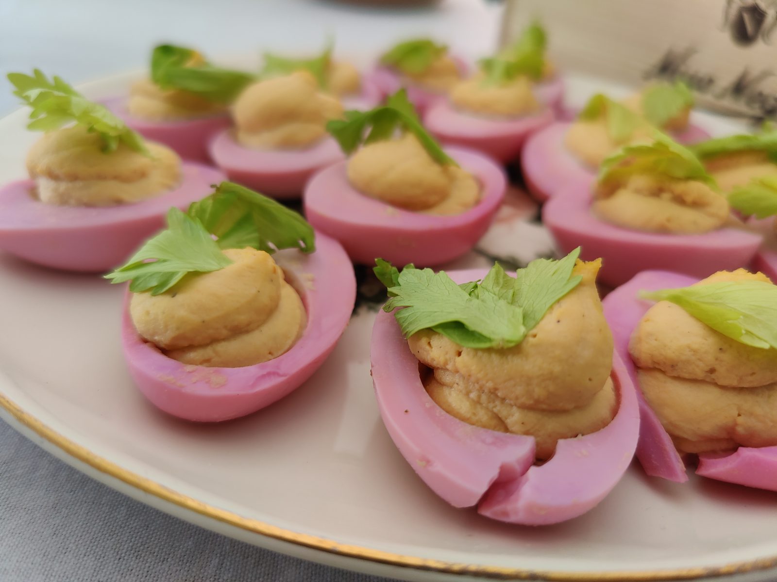 Beet-pickled deviled eggs with bright pink whites and a celery-leaf garnish