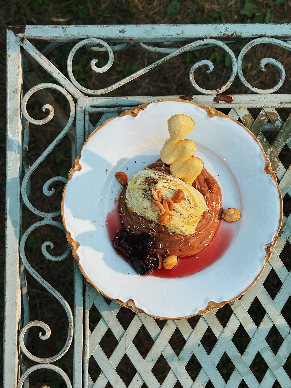 A plated dessert with ice cream and fruit compote on an ornate plate