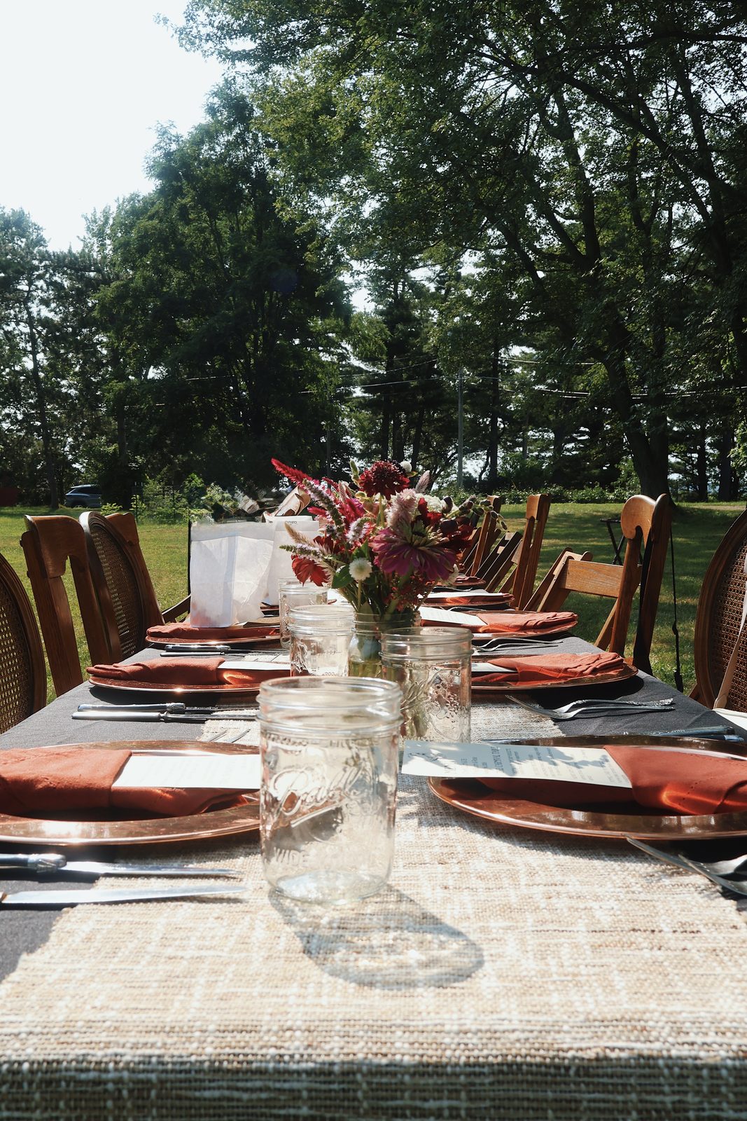 A long farm table set with flowers and place settings for an outdoor dinner