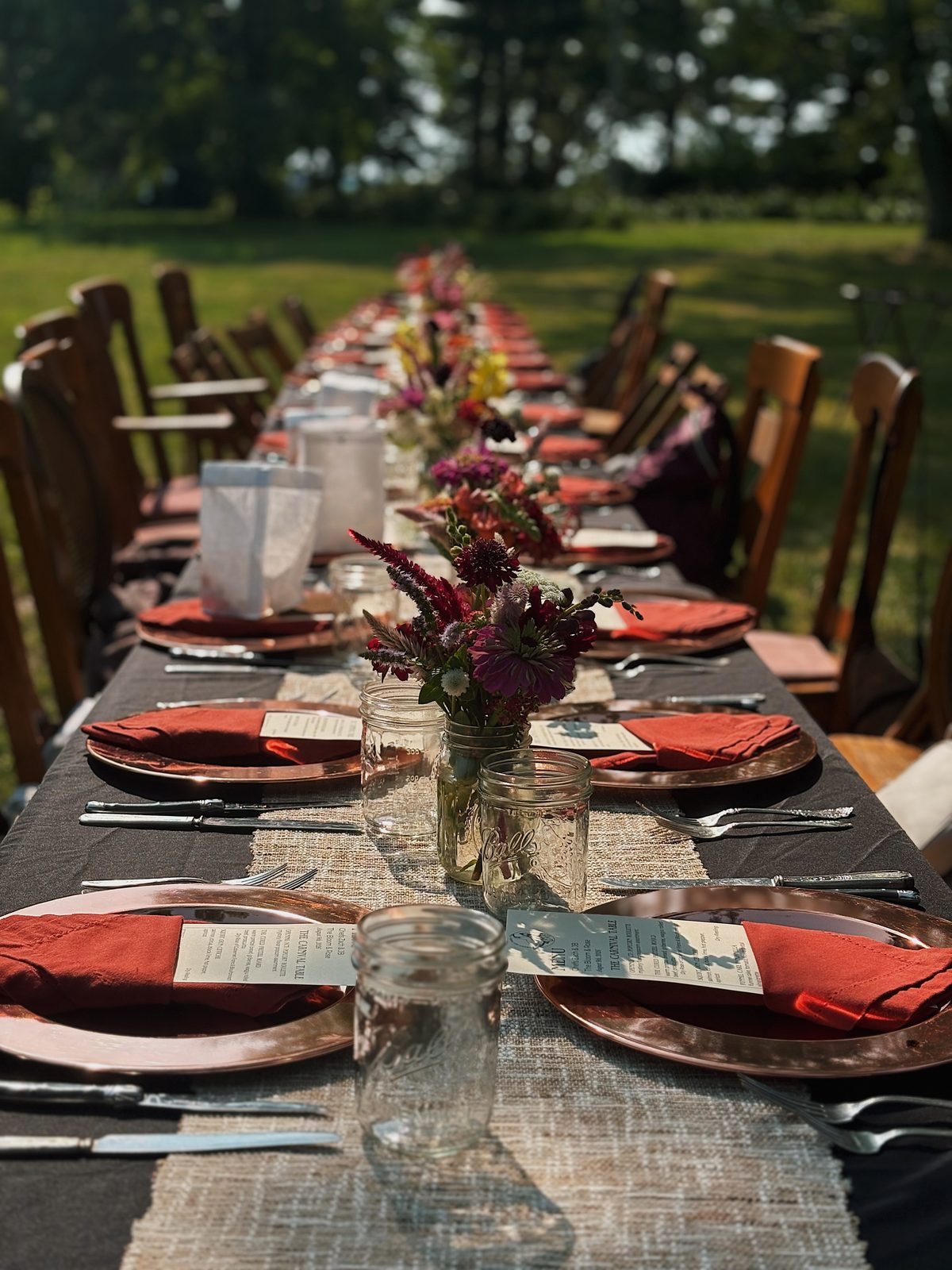 A long banquet table dressed with red napkins and floral centerpieces