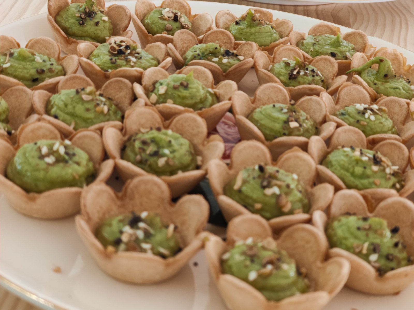 Green pea-mousse tartlets topped with seeds in bite-size pastry shells